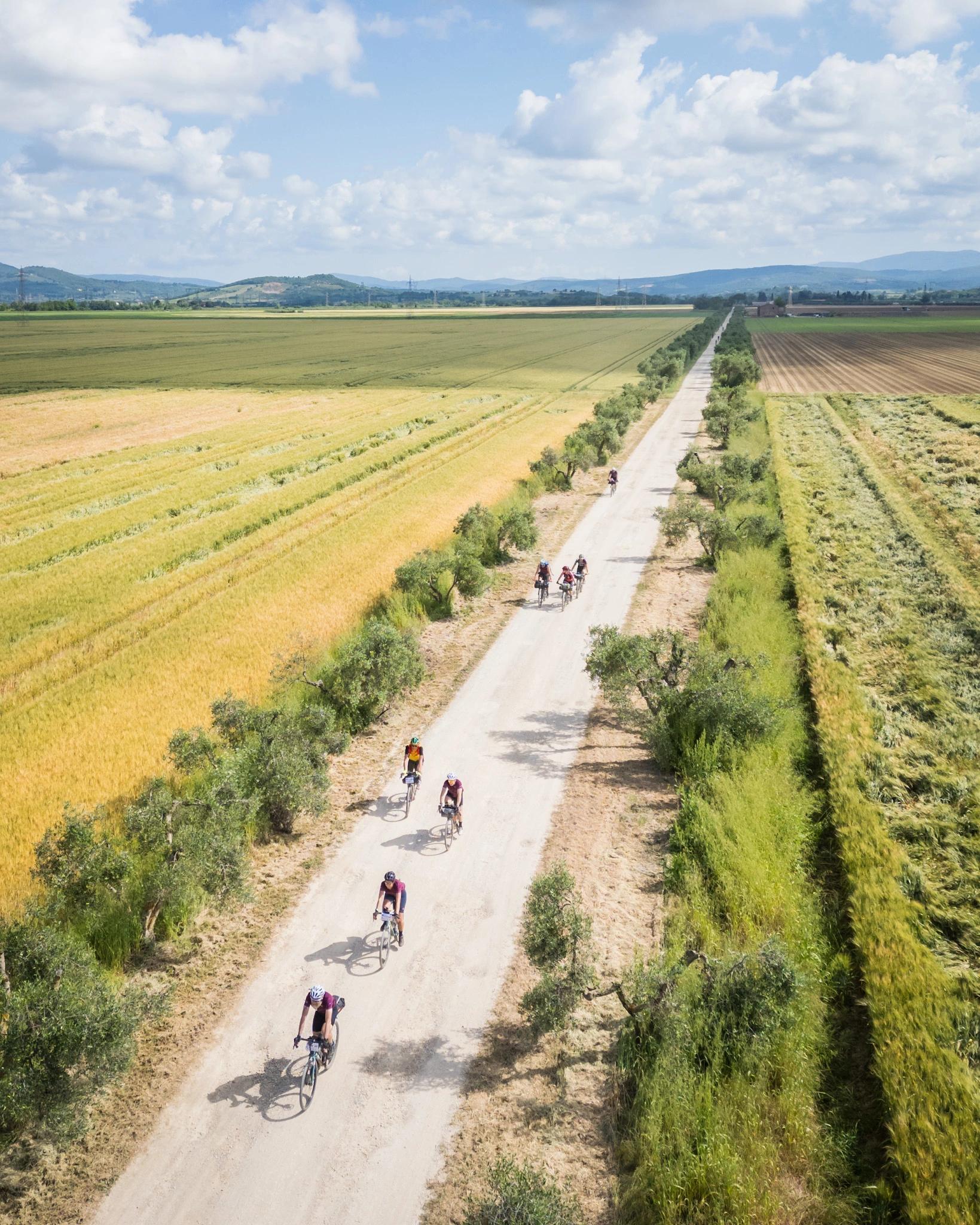 a group of people riding bicycles on a dirt road